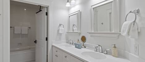 A modern bathroom with a double sink, a large mirror, and a shower area.