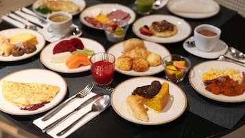 A breakfast buffet with various dishes, including eggs, pastries, and fruits.