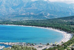 A coastal area with a marina, beach, and mountainous backdrop.