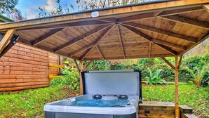 Een hottub onder een houten pergola in een tuin.