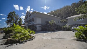 A multi-story building with a balcony, surrounded by greenery and a parking area. - The 5 Tangarane apartments are located in Les Trois Ilets, overlooking the magni (Les Trois-Îlets)
