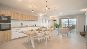 A modern kitchen with wooden cabinets, a dining area with a table and chairs, and a view of mountains through large windows. - The 5 Tangarane apartments are located in Les Trois Ilets, overlooking the magni (Les Trois-Îlets)