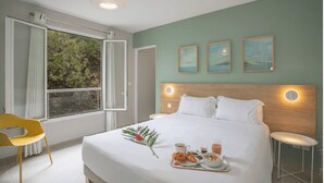 A hotel room with a large bed, a window with curtains, a yellow chair, and a breakfast tray on the bed. - The 5 Tangarane apartments are located in Les Trois Ilets, overlooking the magni (Les Trois-Îlets)