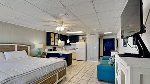 Une chambre d’hôtel compacte comprenant un lit, une kitchenette et un petit coin salon.