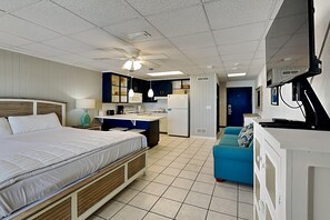 Une chambre d’hôtel compacte comprenant un lit, une kitchenette et un petit coin salon.