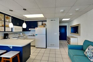 Una cocina moderna con una isla central, electrodomésticos blancos y armarios azules.