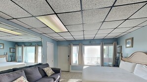 A hotel room with a large bed, a sofa, a window with curtains, and a ceiling with a grid pattern. - Continental #216, | Private Balcony and Gulf Side Pool (Panama City Beach)