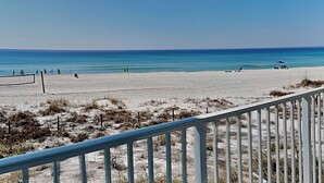 Una spiaggia con cielo sereno, una riva sabbiosa e alcune persone in lontananza.