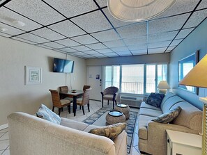 A living room with a sofa, chairs, a TV, and a dining area with a table and chairs.