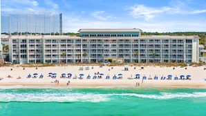 Een strandhotel met meerdere balkons, een zandstrand en uitzicht op de oceaan.