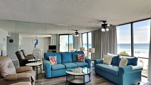 Una sala de estar moderna con un sofá azul, un sillón de cuero marrón y una mesa de centro de vidrio.