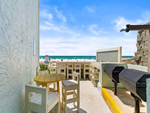 Eine Terrasse mit Tisch, Stühlen, einem Grill und Blick auf den Strand.