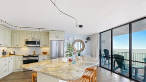 Cozinha moderna com armários brancos, eletrodomésticos de aço inoxidável e uma ilha grande com banquetas de madeira.