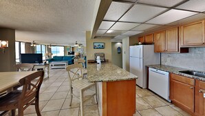 A spacious kitchen with a central island, wooden cabinets, and a dishwasher. - Edgewater Leeward #407 | Gulf Front + Amenities (Panama City Beach)