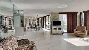 Amplia sala de estar con sofá, televisor y comedor con sillas y mesa.