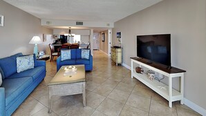 A living room with a blue sofa, a coffee table, and a TV on a stand.