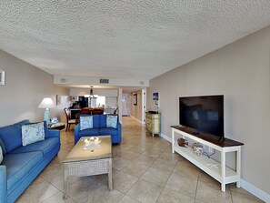 A living room with a blue sofa, a coffee table, and a TV on a stand.