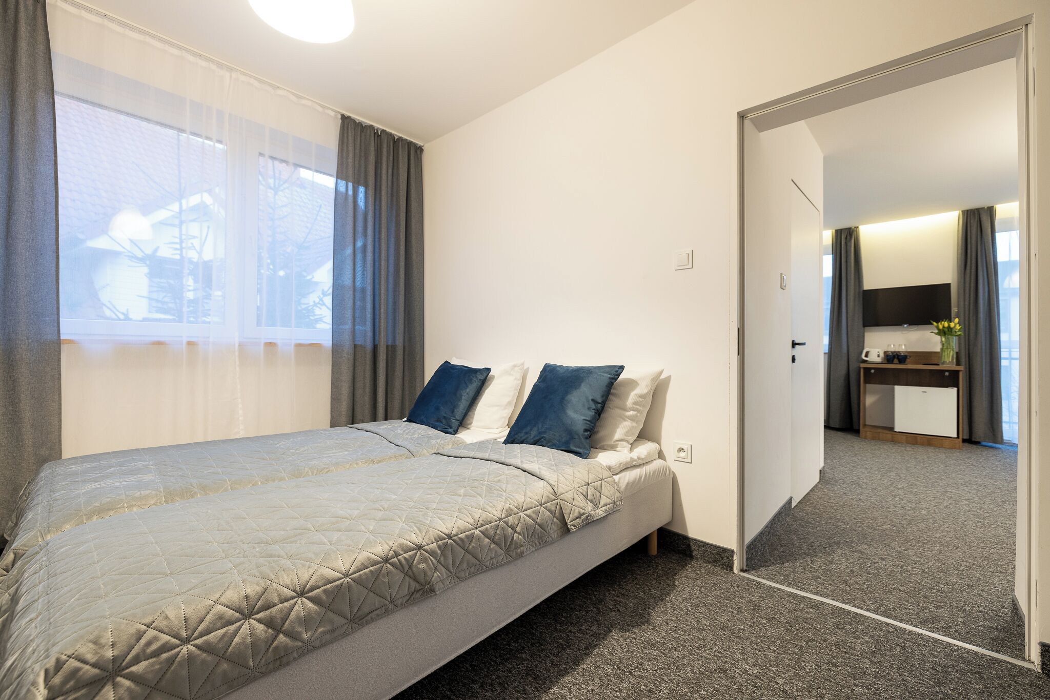 A bedroom with a bed, a desk, and a bathroom visible through an open door.