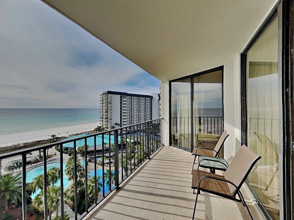 A balcony with a view of a beach and a pool.