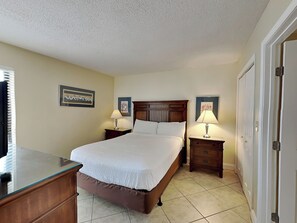A hotel room with a large bed, two bedside tables with lamps, a dresser, and a door.