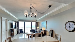 Ein geräumiger Essbereich mit großem Tisch und Stühlen, einer Chandelierleuchtre und Blick auf das Meer durch große Fenster.