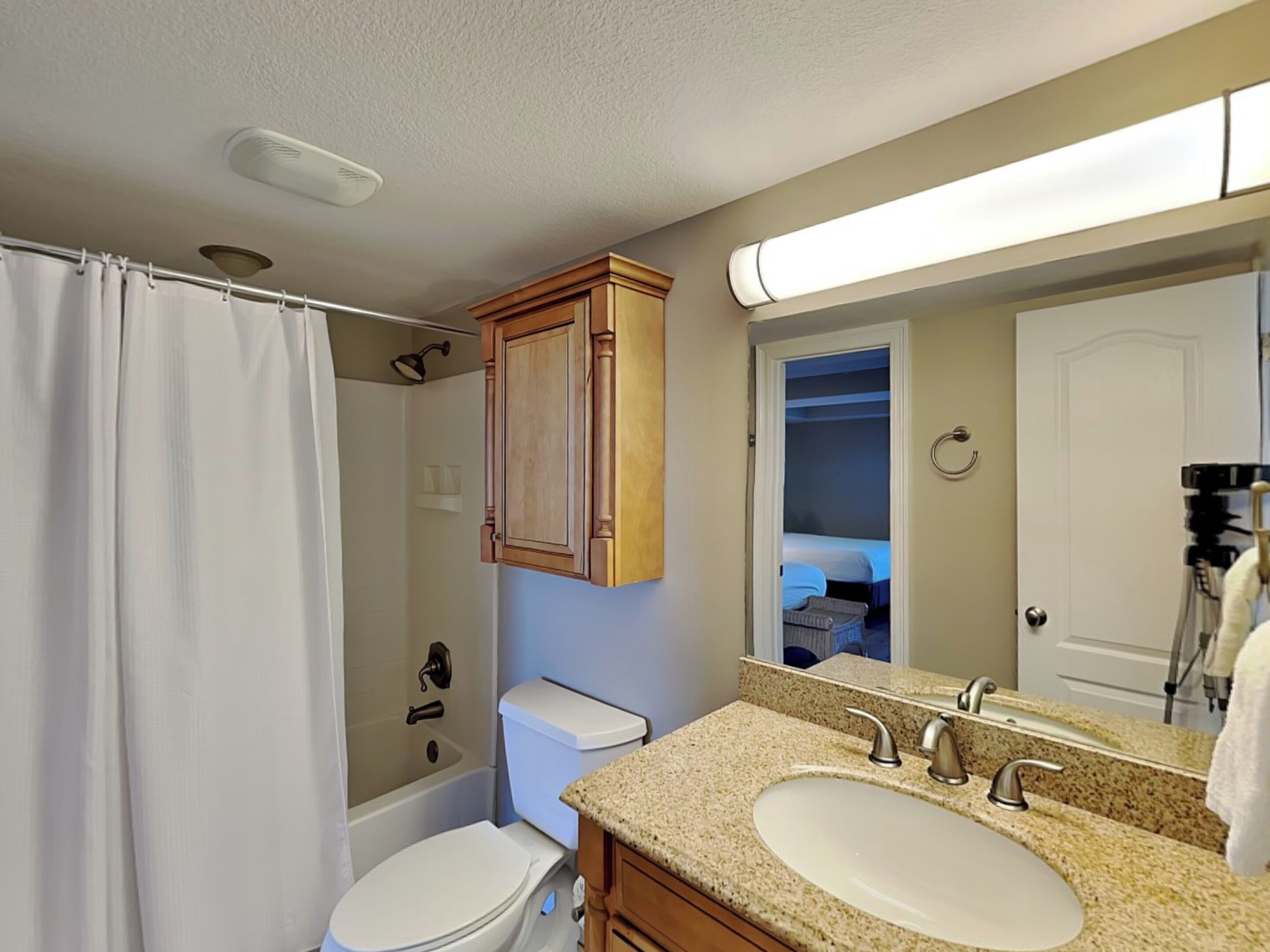 A bathroom with a shower, toilet, vanity with a sink, and a mirror.