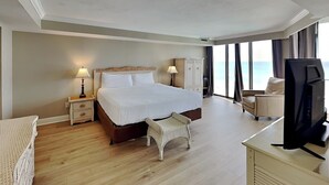 Ein Hotelzimmer mit einem großen Bett, einem Fernseher, einem Schreibtisch und Meerblick.