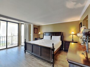 Un dormitorio amplio con una cama grande, un aparador de madera y un balcón con vistas.