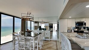 A modern kitchen with a central island, white cabinetry, and a view of the ocean. - Edgewater Tower II #1001 | Amenities & Views Galore! (Panama City Beach)