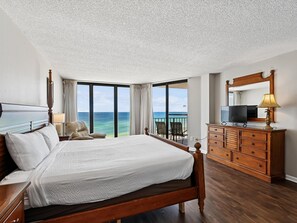 Habitación de hotel con una cama grande, una cómoda, un televisor y vista al océano.