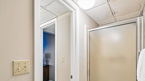 A hallway with a door leading to a room with a blue wall and a wooden floor.