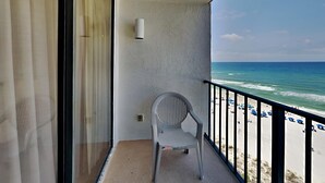 Un balcon donnant sur la plage, une chaise et un luminaire fixé au mur.