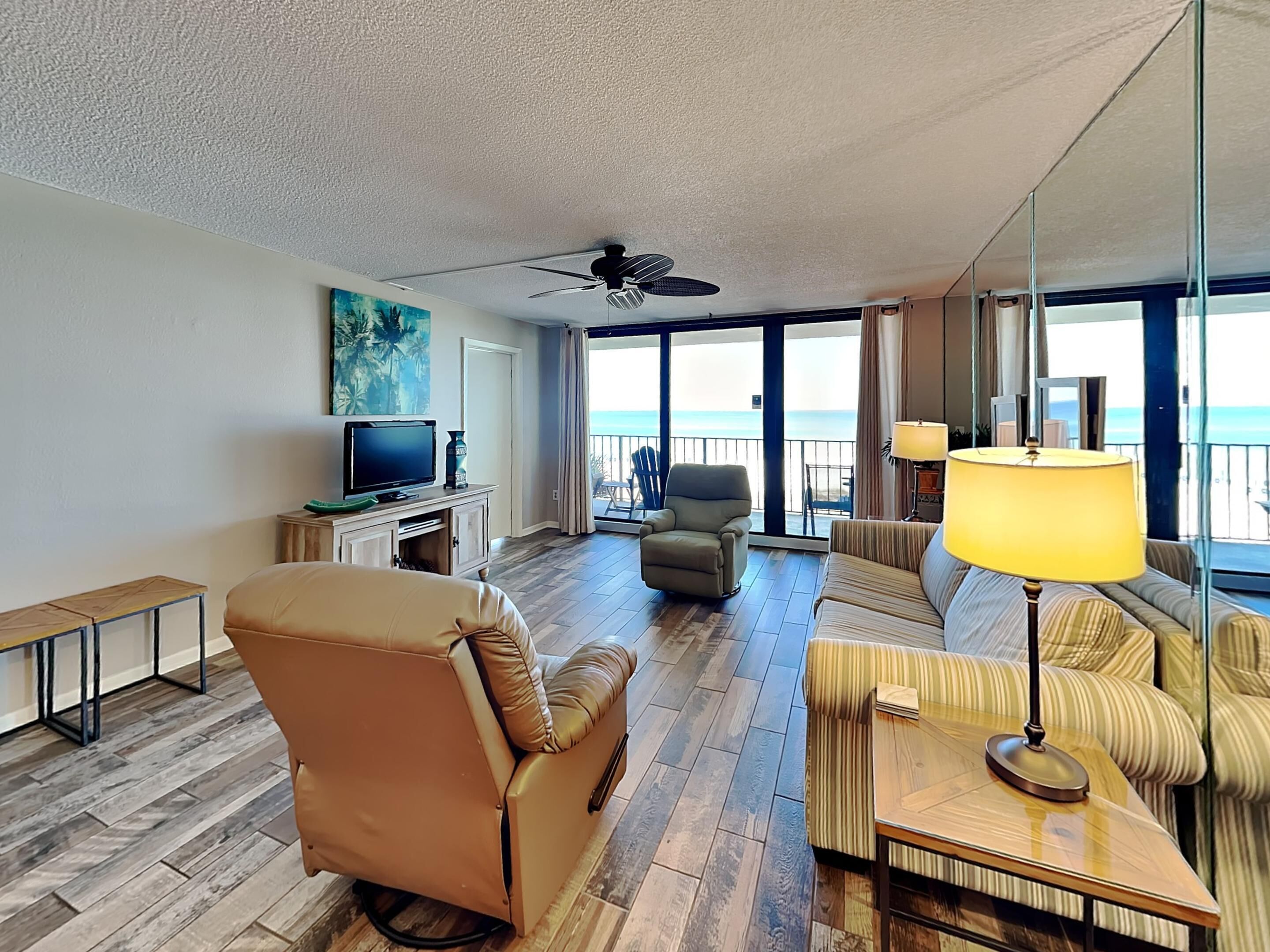 Hotelkamer met een groot bed, een sofa, een stoel, een televisie en een balkon met uitzicht op de oceaan.