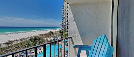 A balcony with a view of a beach and a pool area.