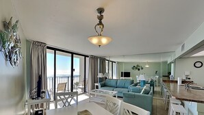 Una sala de estar moderna con comedor, un conjunto de sofá, televisión y balcón con vistas.