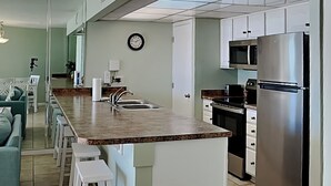 Una cocina moderna con una isla central, electrodomésticos de acero inoxidable y una zona de comedor con sofá y sillas.