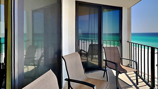 Un balcon avec vue sur l’océan, une chaise et une table.