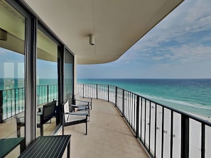 Ein Balkon mit Blick auf das Meer, einem Tisch und Stühlen.