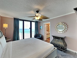 Ein Hotelzimmer mit Bett, Deckenventilator, Schminktisch und Blick auf den Ozean.