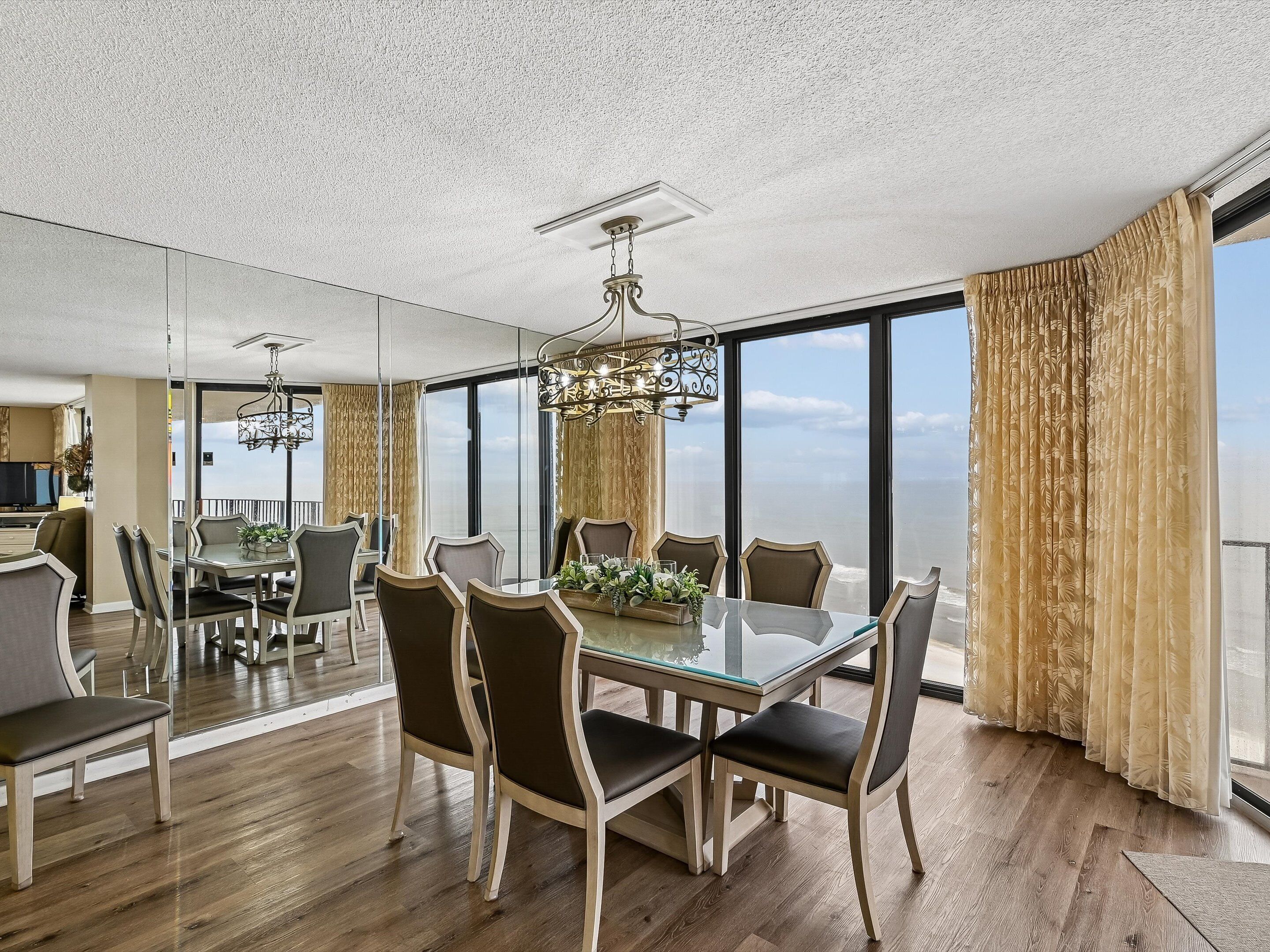 A dining area with a glass table, chairs, and a chandelier.
