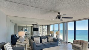 Amplia sala de estar con un ventanal que ofrece vista al océano, ventilador de techo y diseño interior moderno.