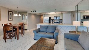 Una sala de estar moderna con comedor, cocina y un espejo grande.