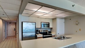 Cocina moderna con refrigerador de acero inoxidable, microondas y estufa, encimera blanca y salpicadero de azulejos.