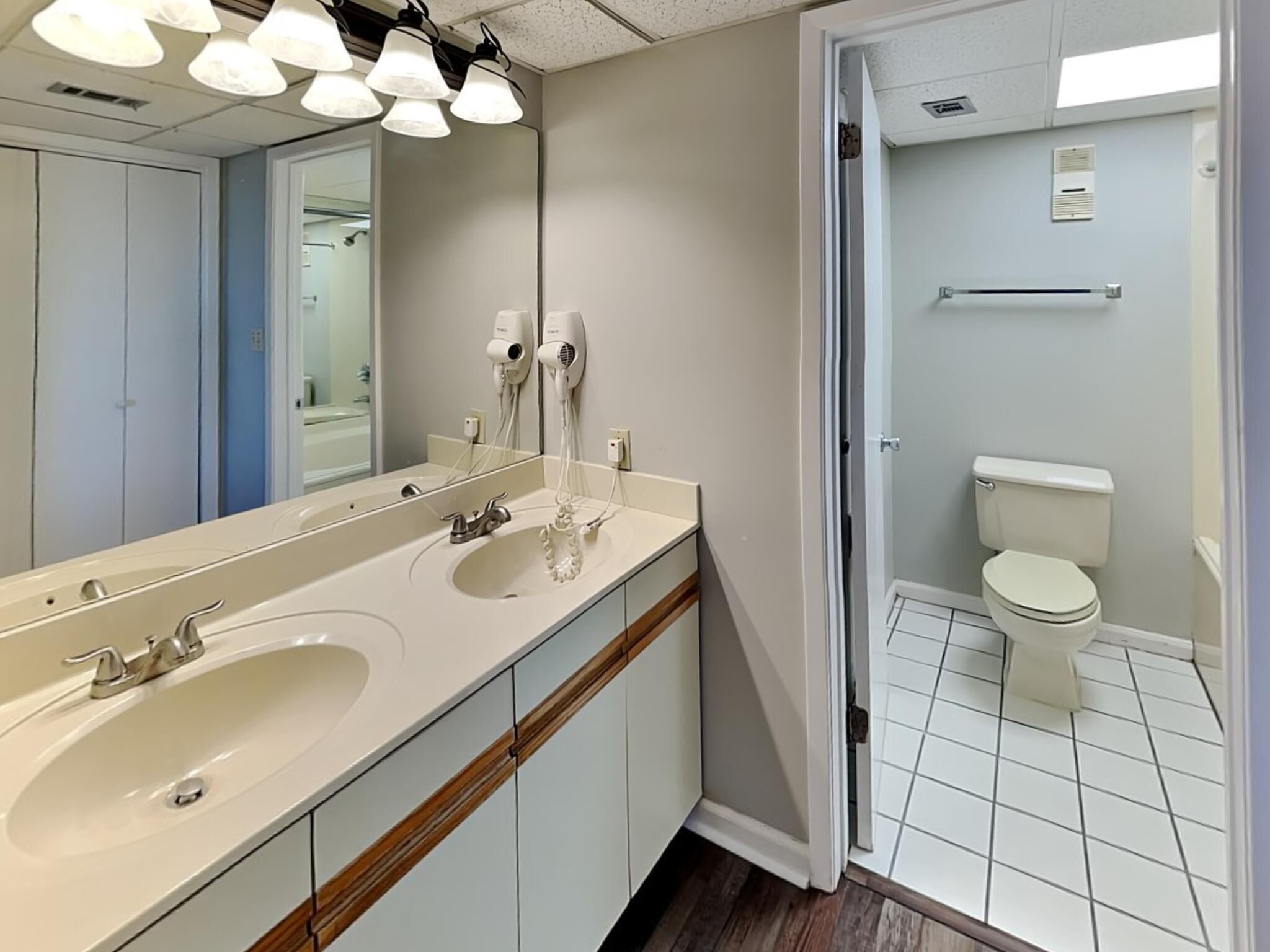 Une salle de bain avec un double lavabo, un miroir et des toilettes.