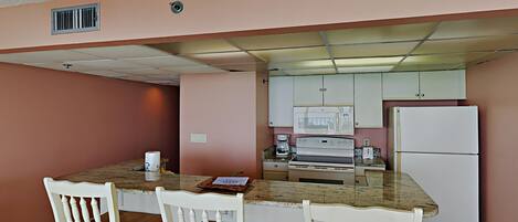 A kitchen with a granite countertop, white cabinetry, and a white refrigerator.