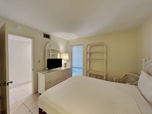 Un dormitorio con cama, cómoda, televisor y estanterías.