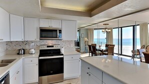 A modern kitchen with white cabinetry, a built-in microwave, and a stainless steel oven.
