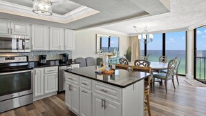Une cuisine moderne avec des meubles blancs, des appareils en acier inoxydable et un grand îlot central.