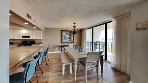 Een moderne keuken met witte kasten, een groot eiland en een eethoek met een lange tafel en stoelen.