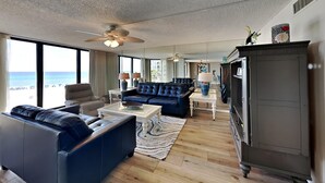 Een ruime woonkamer met een grote bank, een bijzettafeltje en uitzicht op de oceaan.